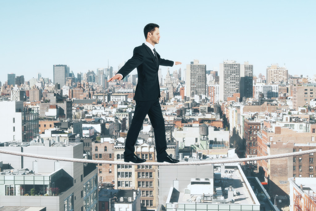 A business owner walking a tightrope above a city, symbolizing the difficulty of doing business