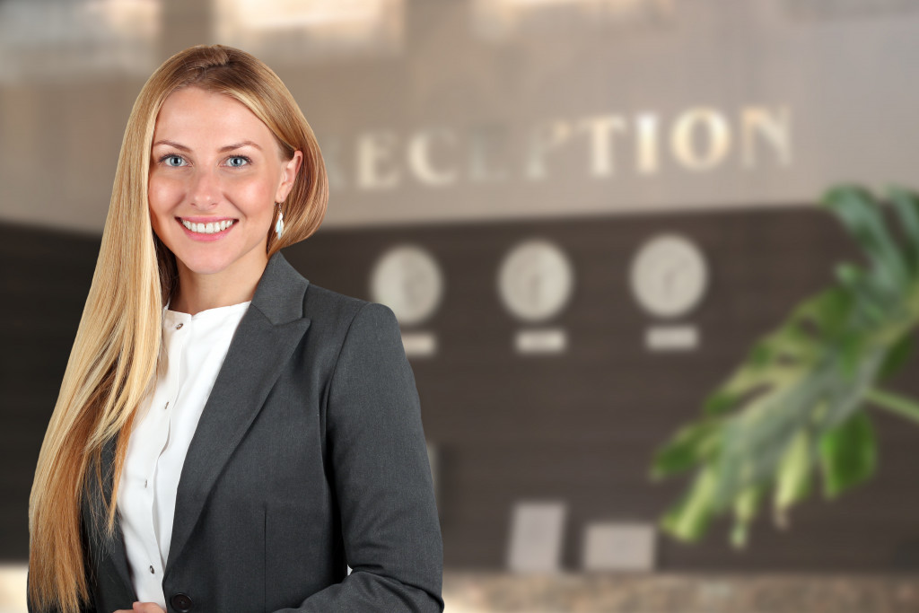 smiling female receptionist in front desk of hotel or property