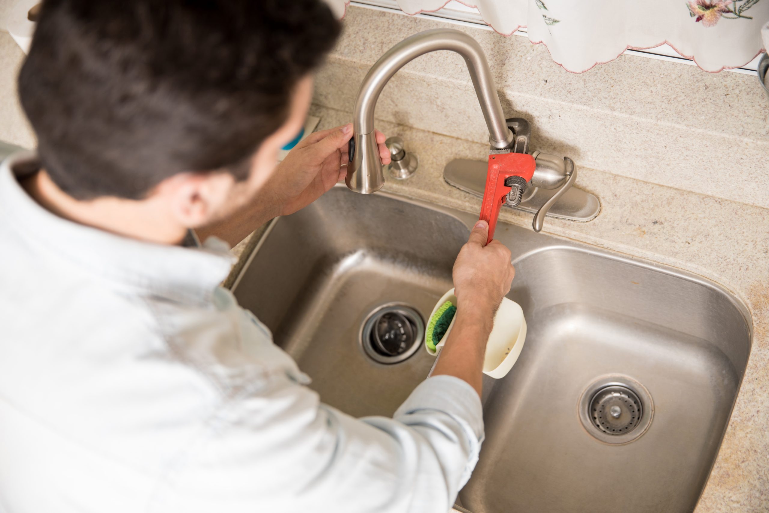 man fixing a kitchen faucet