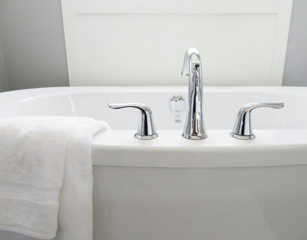 white ceramic bathtub with a faucet and two handles